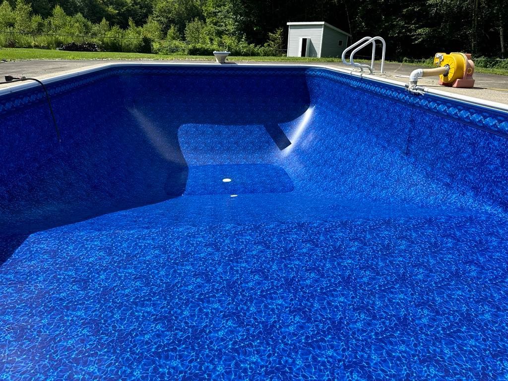 A large swimming pool with a blue liner and stairs.
