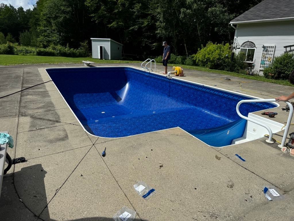 A large blue swimming pool is being built in a backyard.