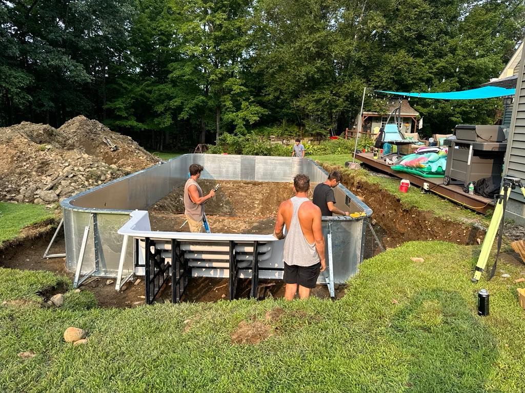 A group of men are working on a swimming pool in a backyard.