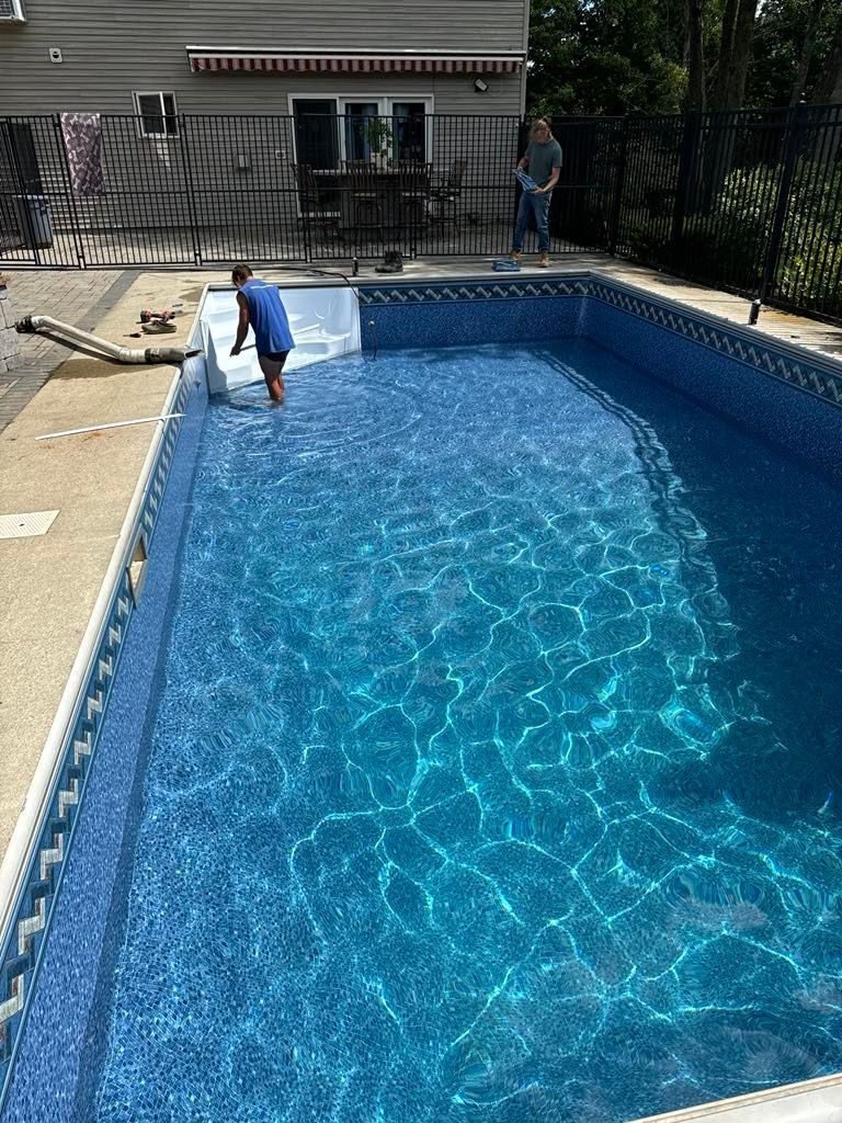 A man is standing next to a large swimming pool.