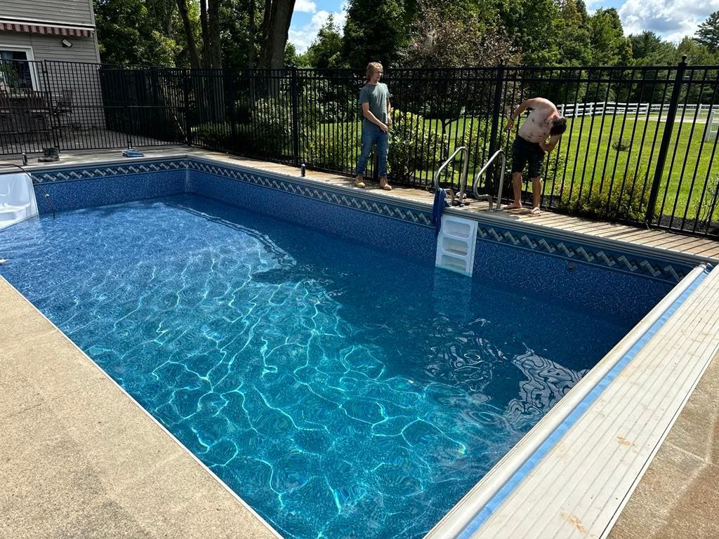 A man and woman are standing next to a swimming pool.