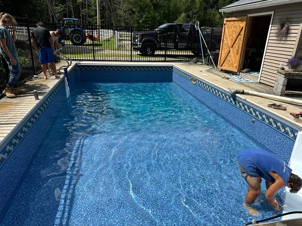 A man is kneeling in the water of a swimming pool.