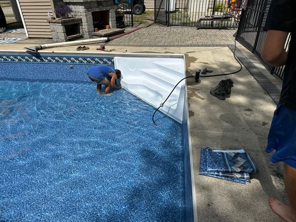 A man is working on the side of a swimming pool.