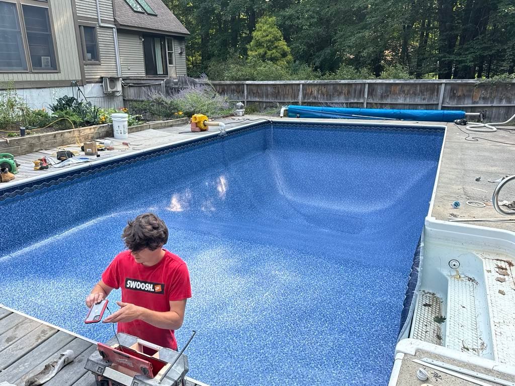 A man in a red shirt is working on a swimming pool.