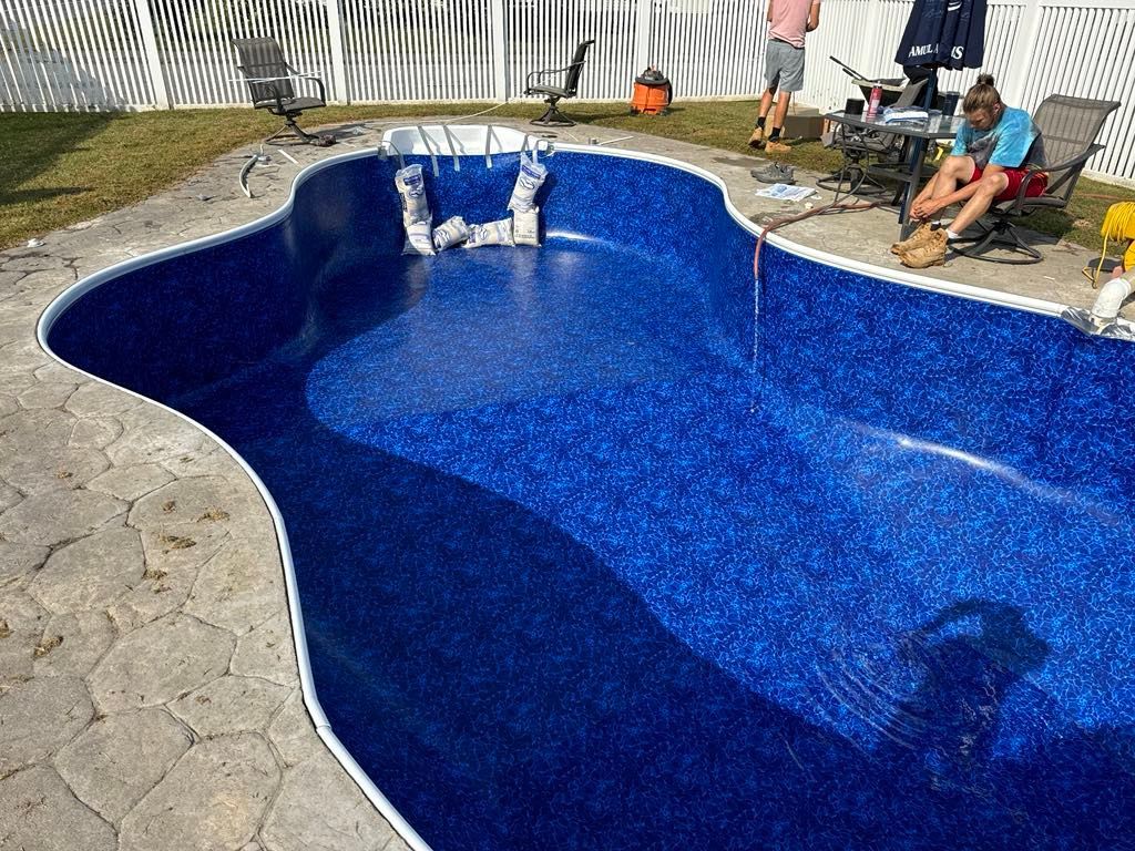 A man is sitting on the side of a swimming pool.