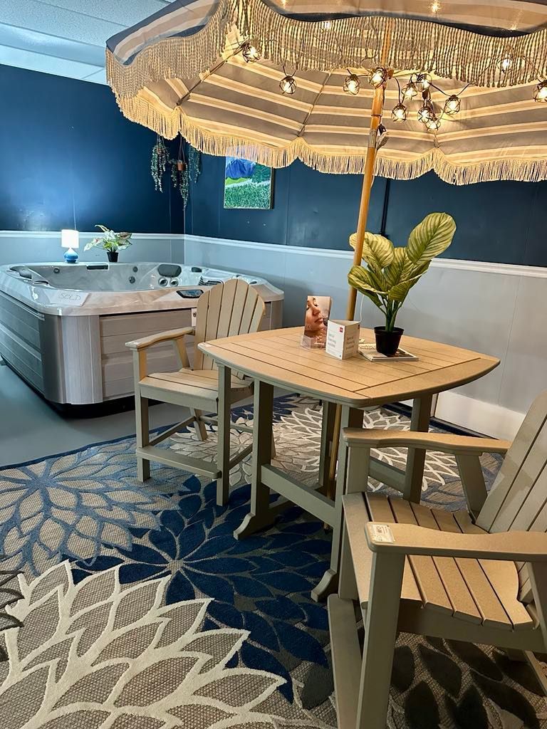 A table and chairs under an umbrella in a room with a hot tub.