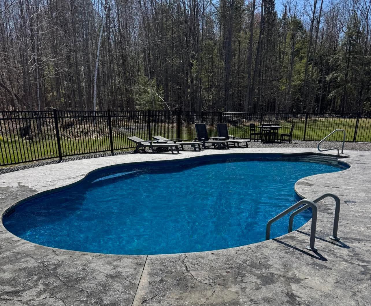 A large swimming pool surrounded by chairs and a fence