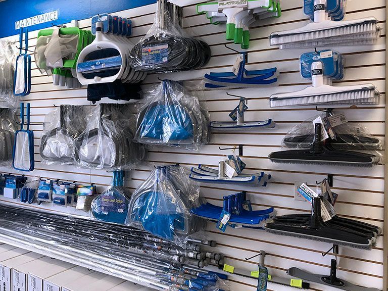 A wall filled with a variety of pool cleaning equipment.