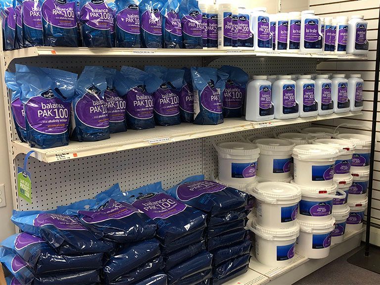 A store shelf filled with buckets and bags of chemicals.