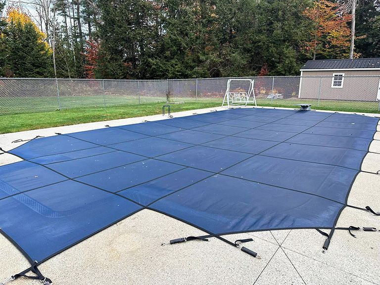 A blue pool cover is sitting on top of a concrete pool.