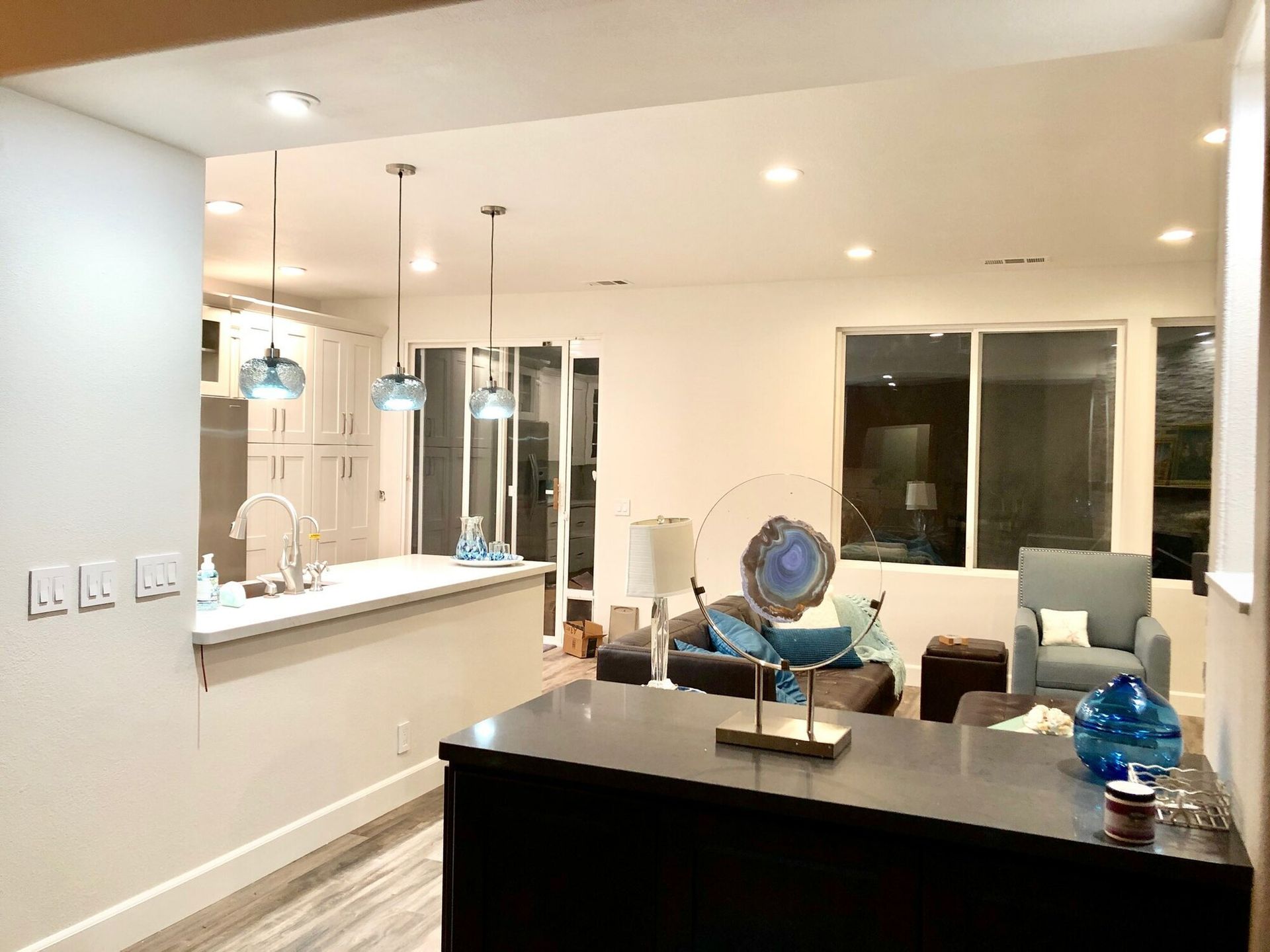 A living room and kitchen in a house with a large island in the middle of the room.