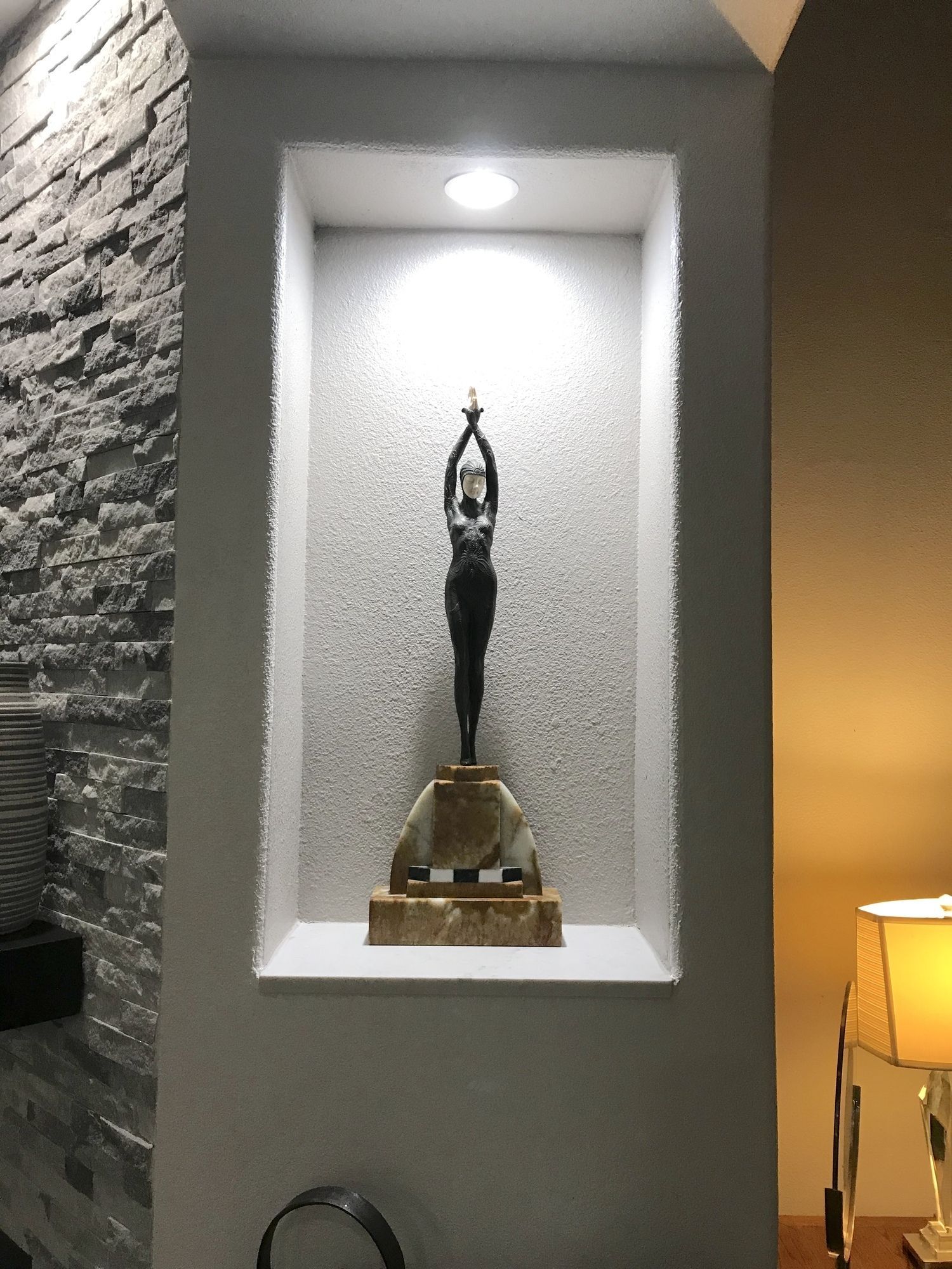 A statue of a woman is sitting in a niche on a wall.