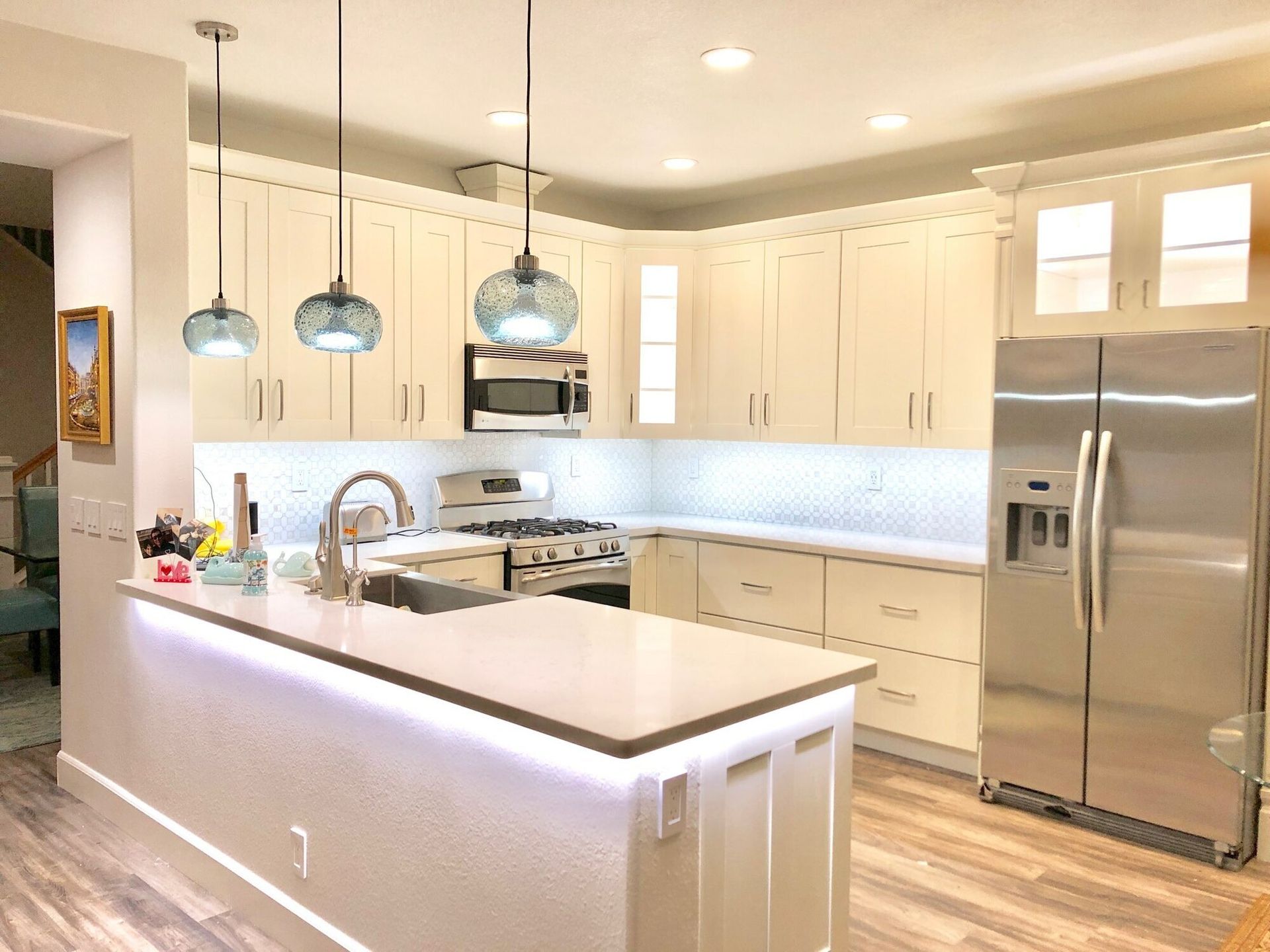 A kitchen with white cabinets , stainless steel appliances , a refrigerator and a sink.