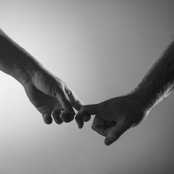 Two hands, index fingers hooked together in a pinky promise. Black and white.