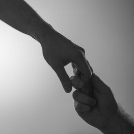 Two hands reaching out, fingers touching.