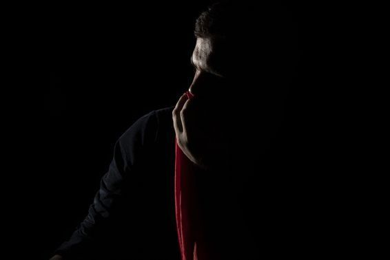 Silhouette of a person with a red cape, dark background.