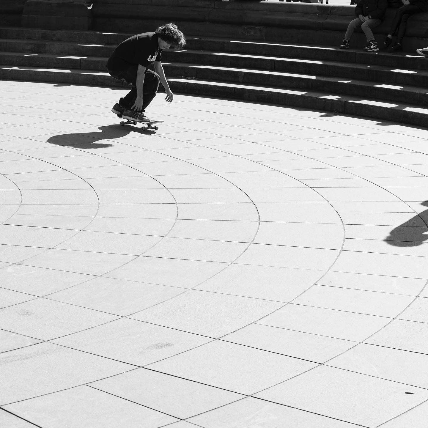 Person skateboarding on a curved, tiled surface near steps.