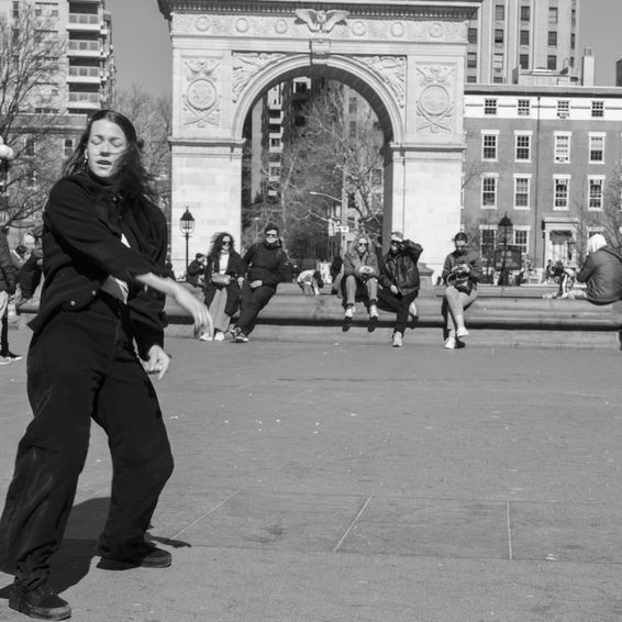 Person dancing in front of Washington Square Arch, NYC. Black and white photo.