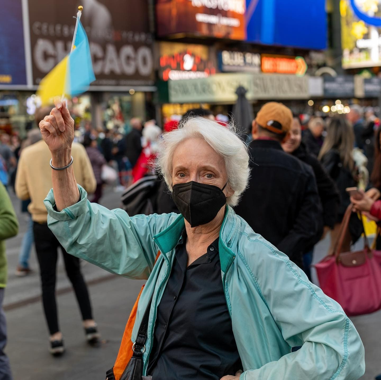 Woman in mask waving Ukrainian flag in Times Square.