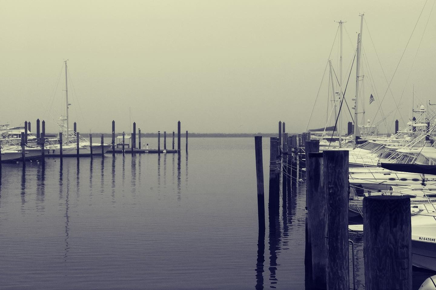Dock with boats on calm water under a gray, overcast sky.