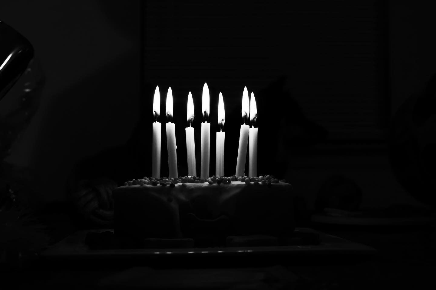 Cake with nine lit candles in a dark setting.