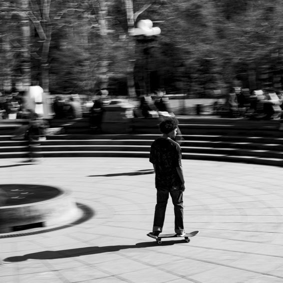 Boy skateboarding in a park, blurred background, black and white.