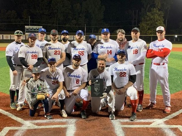 Baseball glove with ball on green grass, with blurred baseballs in the background.