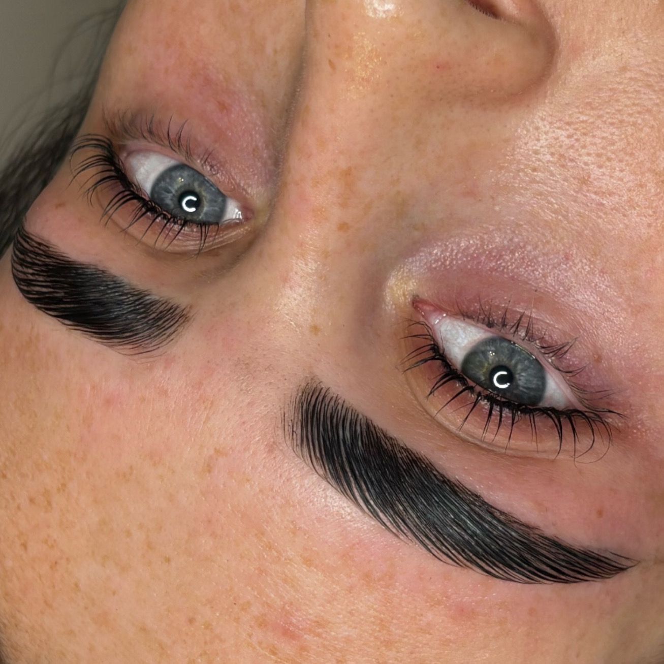A close up of a woman 's face with blue eyes and black eyebrows.