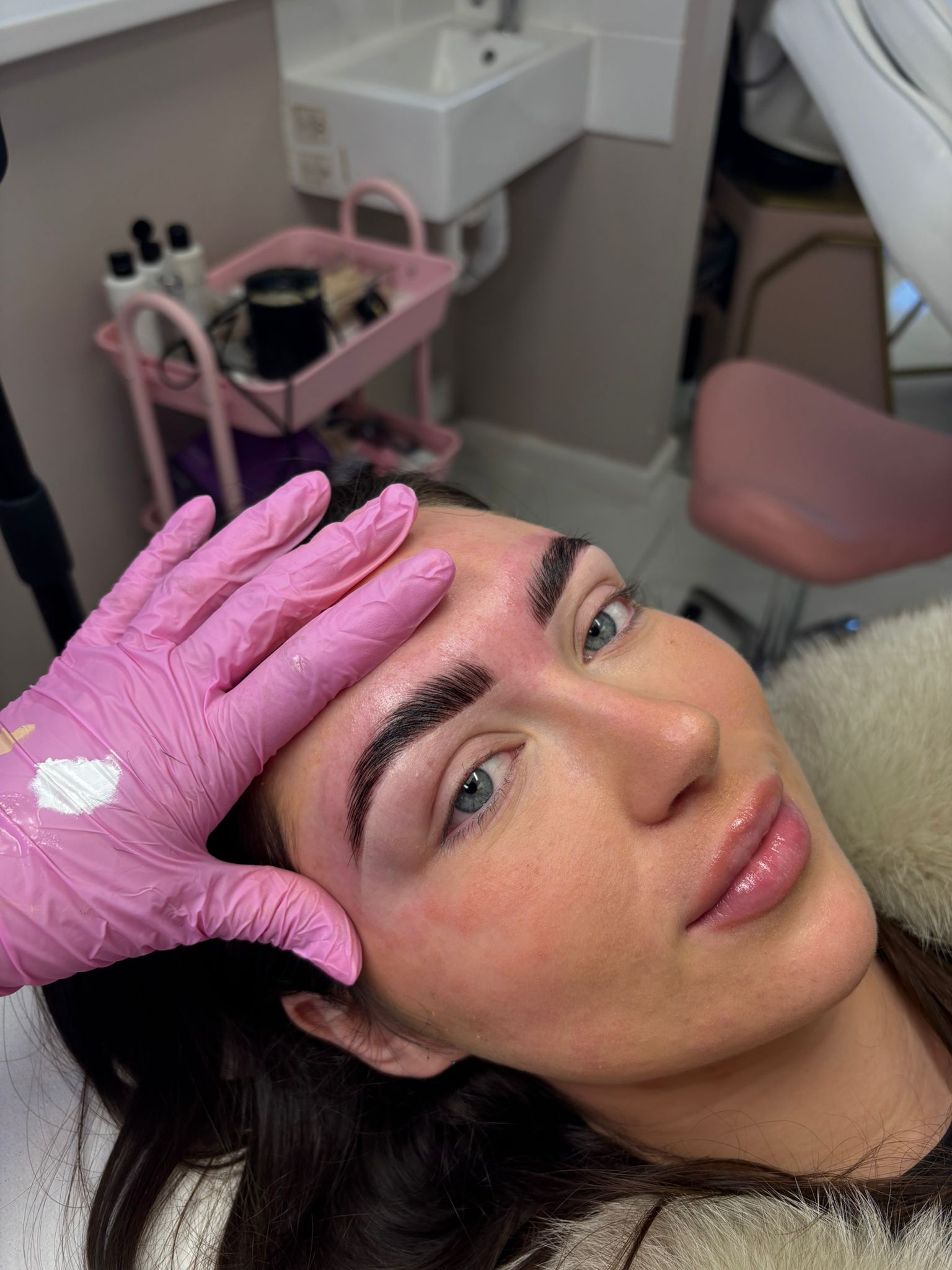A woman is getting her eyebrows done in a salon.