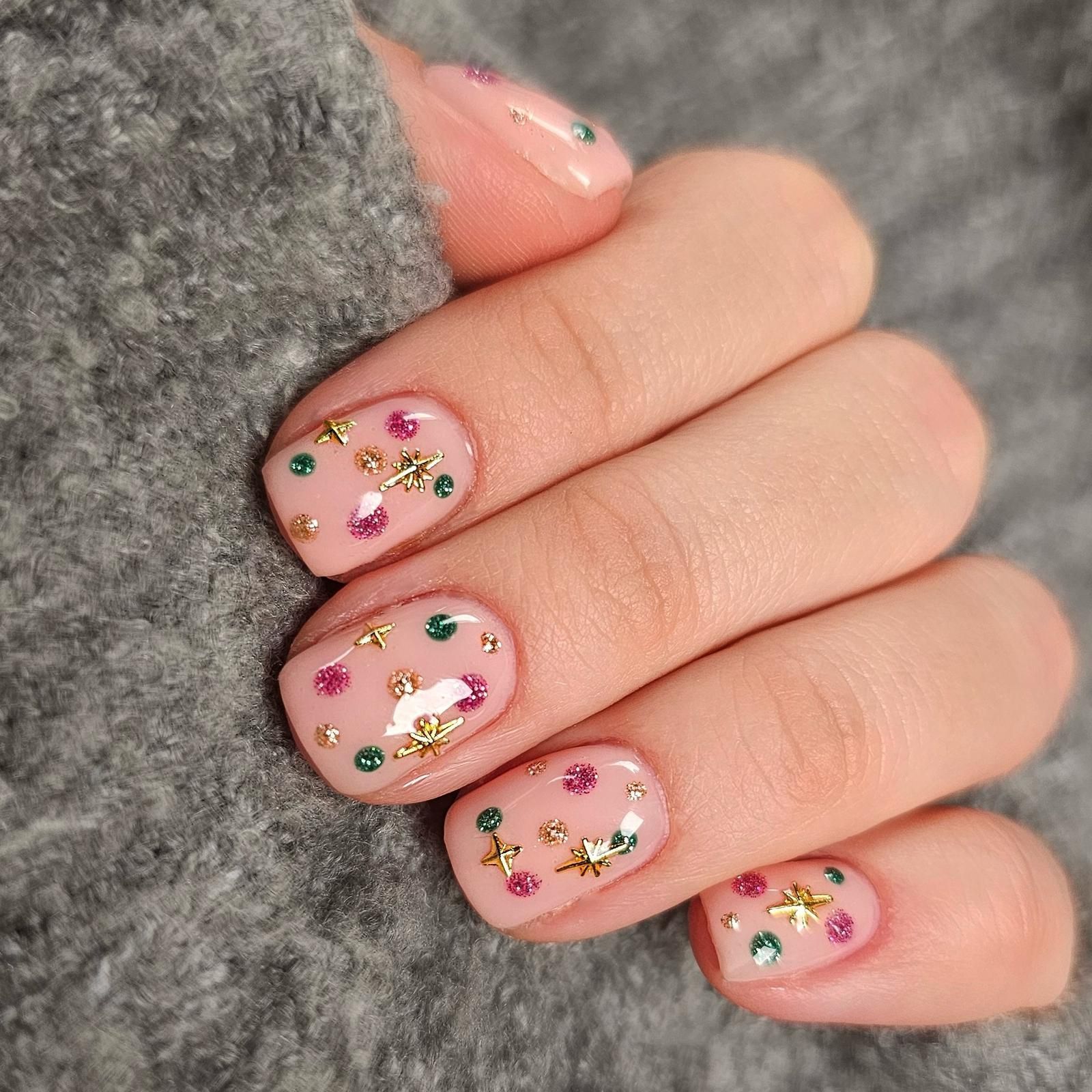 A close up of a person 's nails with a sweater in the background.