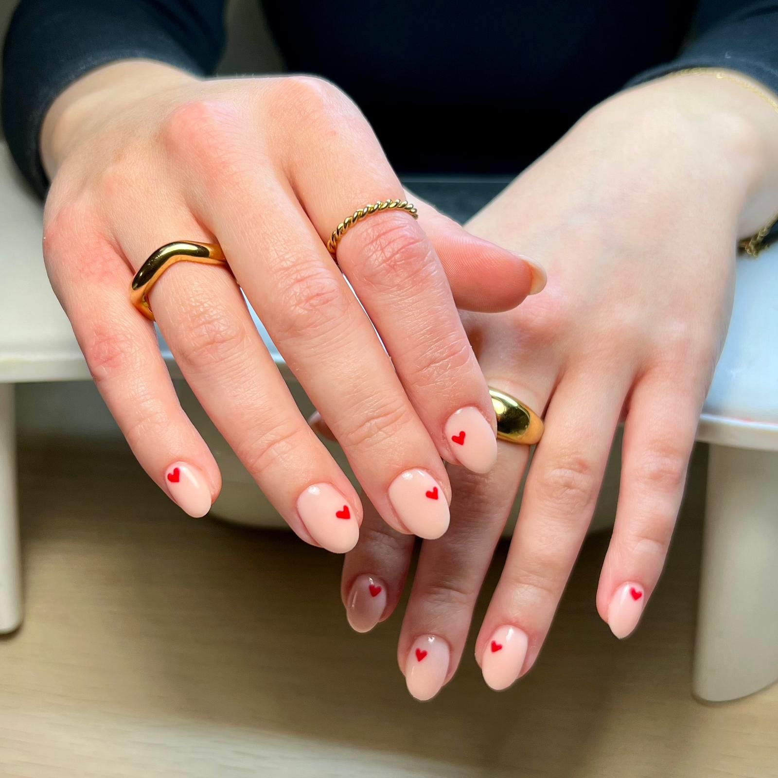 A woman 's hands with pink nails and red hearts on them