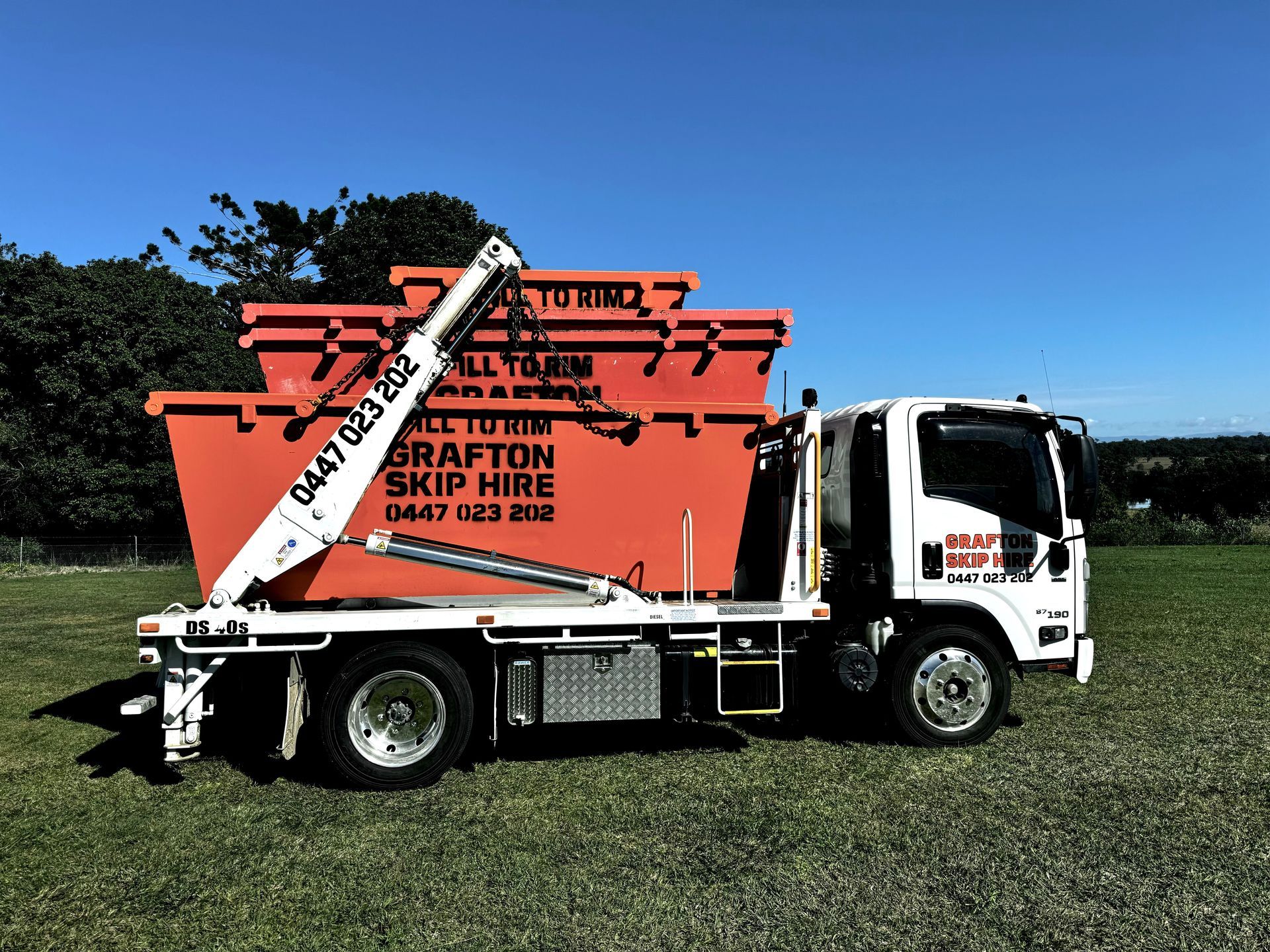 Two Yellow Dumpsters Are Sitting on Gravel in Front of a Row of Houses — Grafton Skip Hire–Zims Bins in South Grafton, NSW