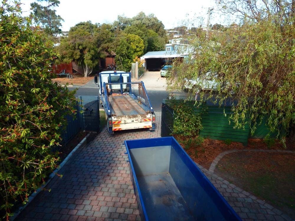 A Blue Dumpster Sits Next to a Truck on a Driveway — Grafton Skip Hire–Zims Bins in South Grafton, NSW