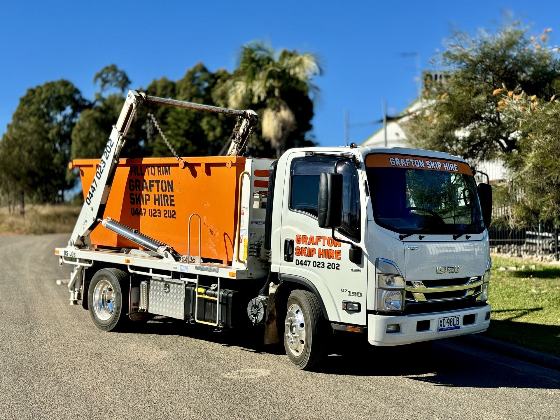 A Green Dumpster Filled With Bricks is Sitting in the Grass — Grafton Skip Hire–Zims Bins in South Grafton, NSW