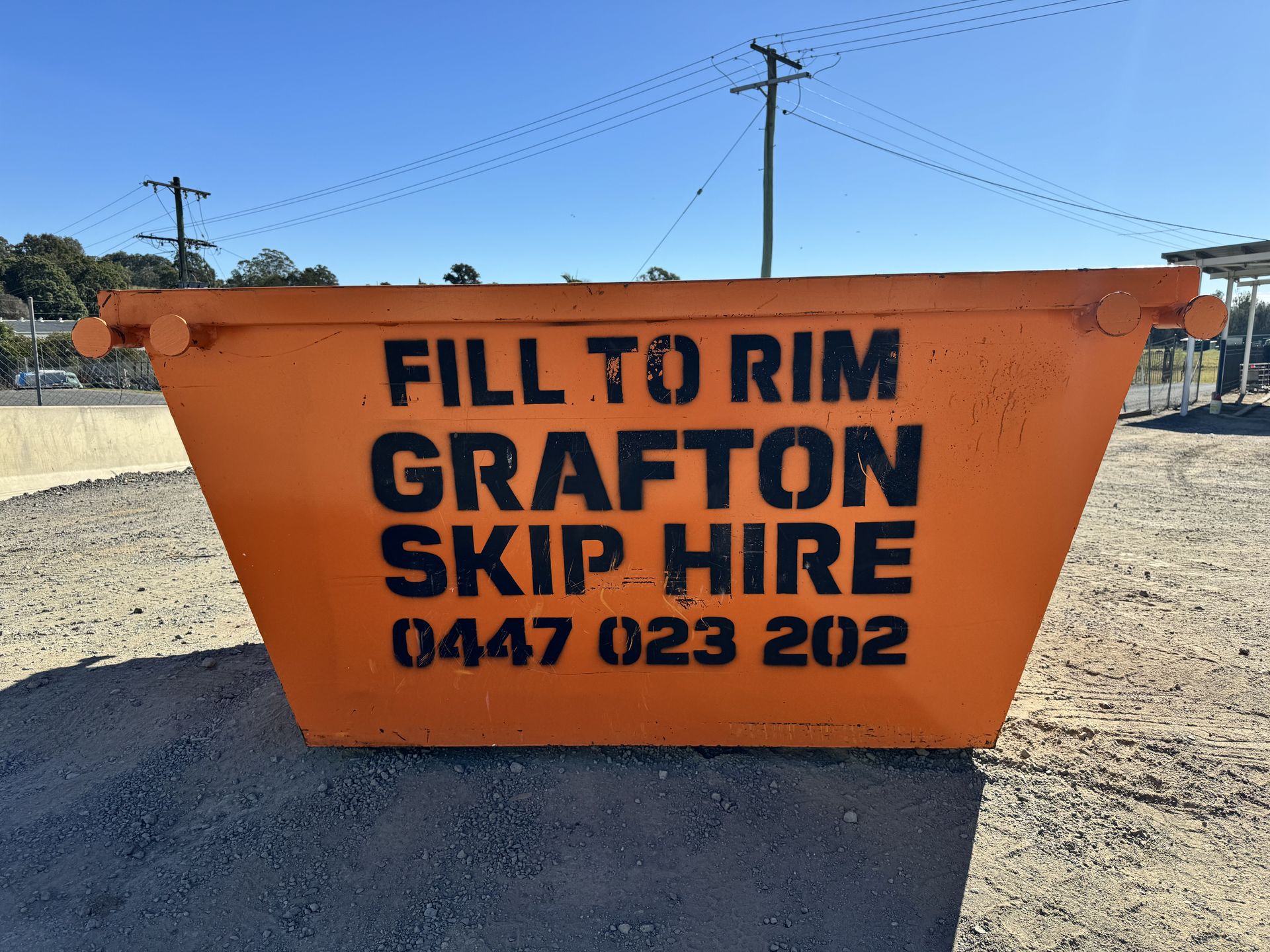 A Yellow Dumpster is Sitting in Front of a Brick Building — Grafton Skip Hire–Zims Bins in South Grafton, NSW
