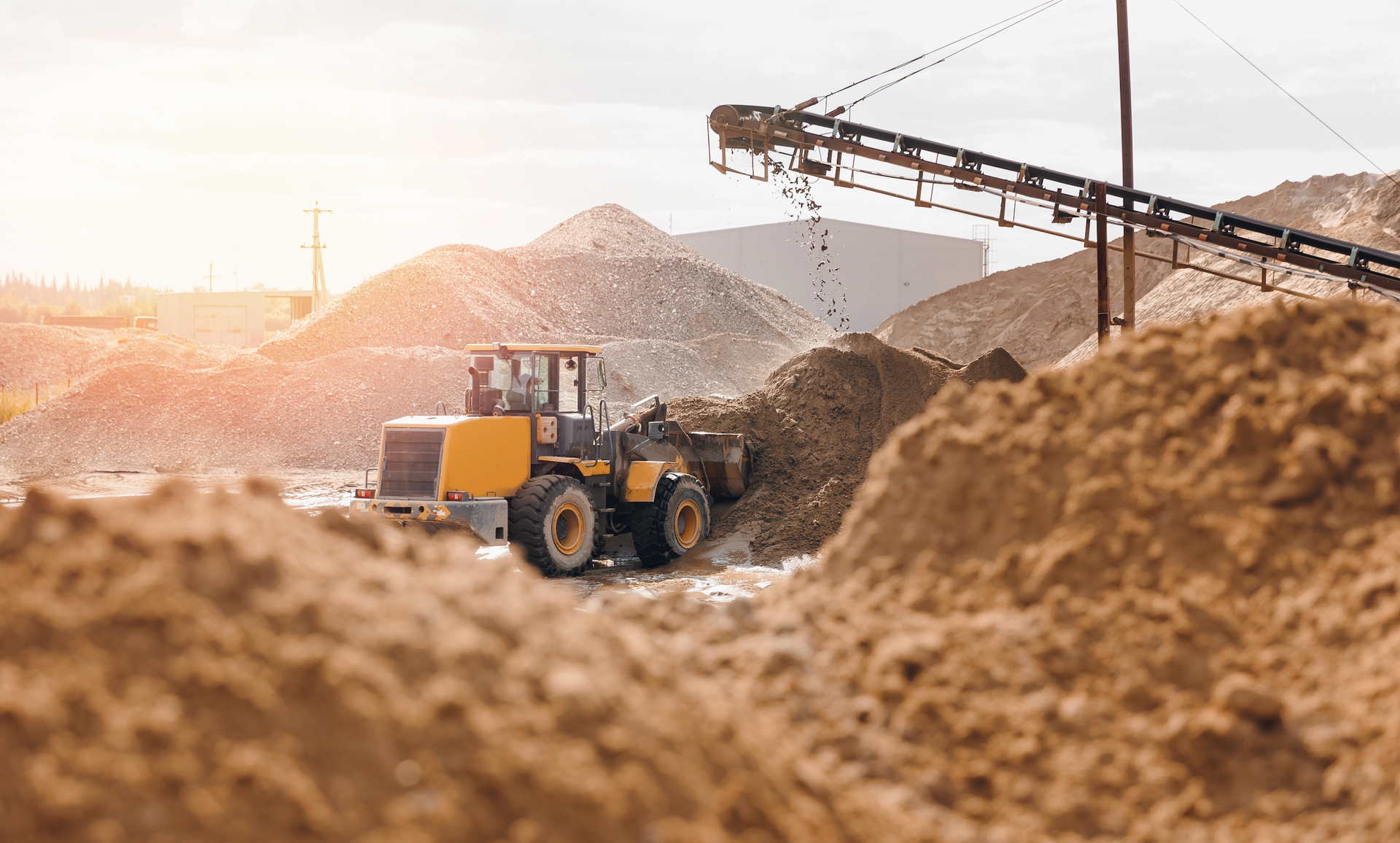 A bulldozer is driving through a pile of sand in a quarry.