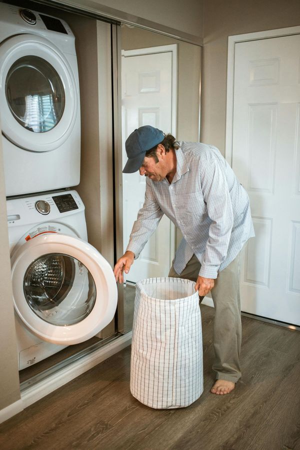 A man is putting clothes in a washing machine in a laundry room.