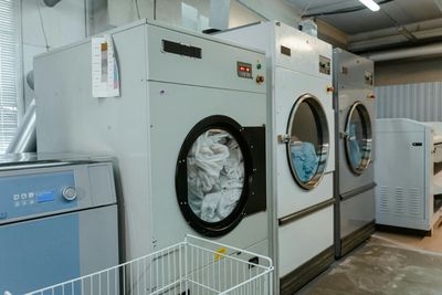 A row of washing machines in a laundromat filled with clothes.