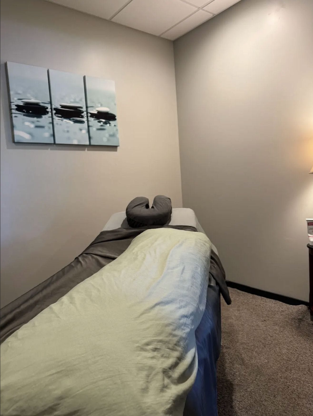 A massage table in a room with three paintings on the wall.