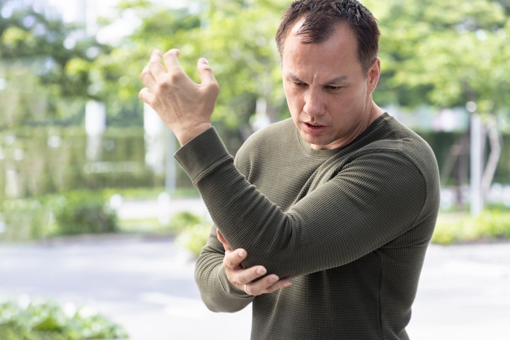 A man is holding his elbow in pain.