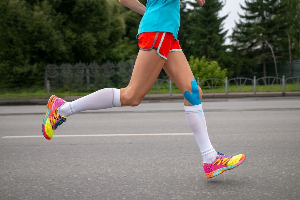 woman running a marathon with athletic tape around her knee area to help with runner's knee