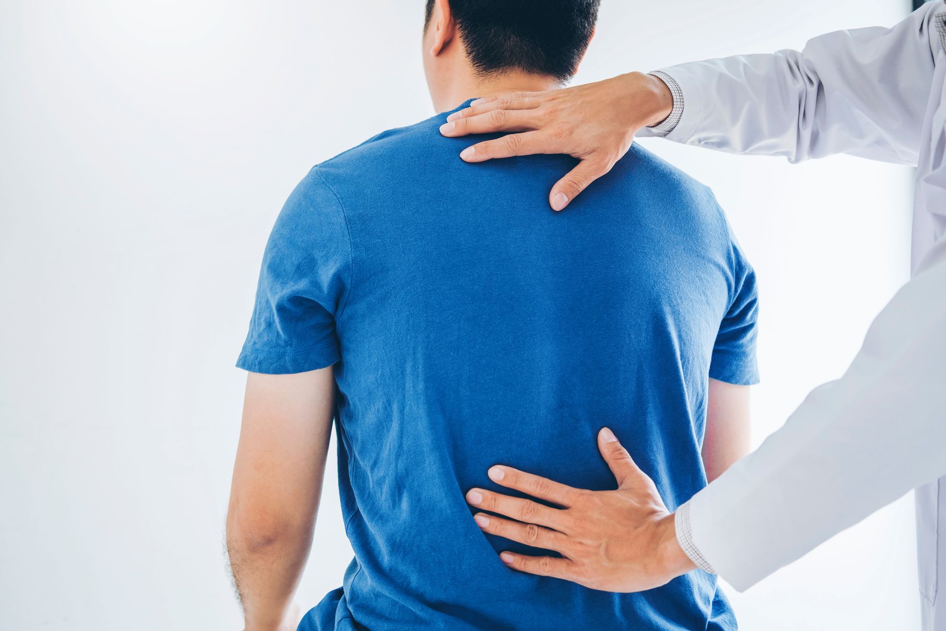 Chiropractor uses his hands to feel his patient's back to help fix lower back pain