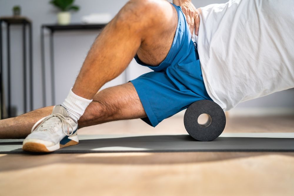 A man is using a foam roller on his leg.