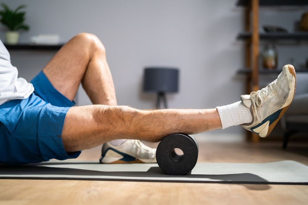 A man is using a foam roller on his leg.