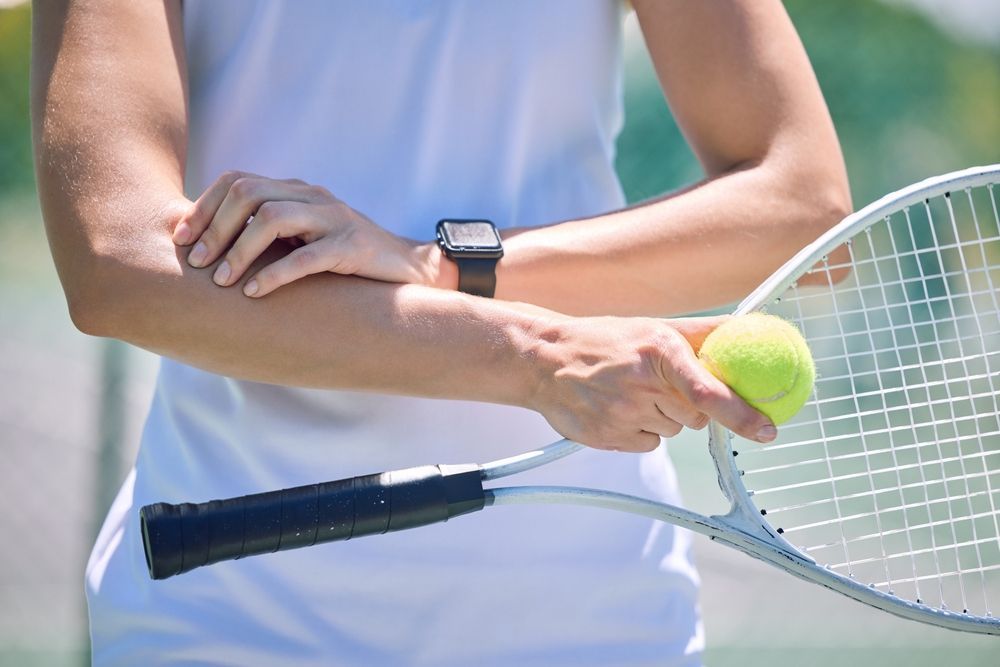 A woman is holding a tennis racquet and a tennis ball.