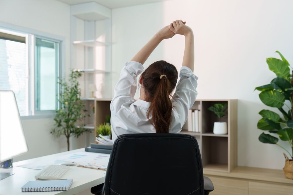 Person stretching at a desk in a bright home office
