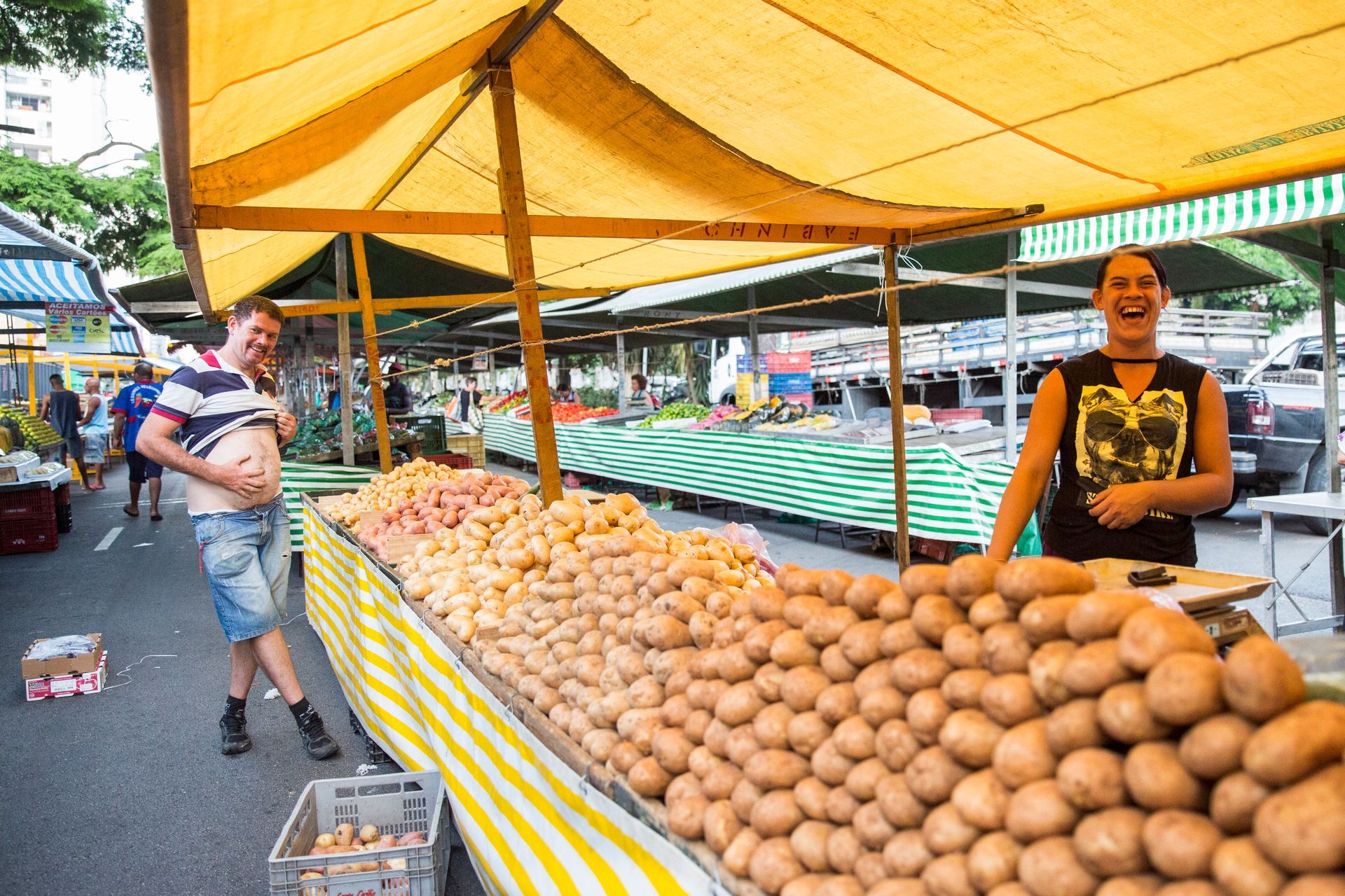 Fotografia autoral de feira livre em São Paulo — detalhe de barraca batata e feirante