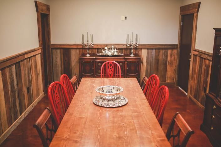 Wood-paneled dining room with a long wooden table, red chairs, and decorative plates on the table