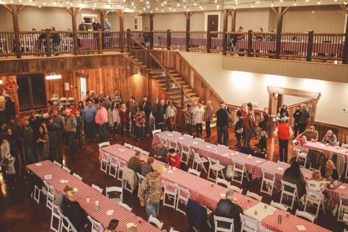 Crowded banquet hall with rows of tables and people mingling on two levels