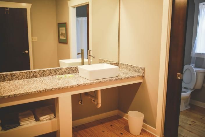 Empty bathroom vanity with granite countertop, mirror, and toilet visible in the background.